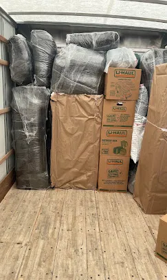 Mover securing and wrapping wooden dresser with padded blankets
